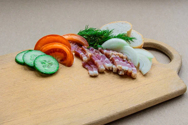 Domuz yağı, soğan, domates, salatalık, ahşap bir tahtanın üzerinde dereotu.