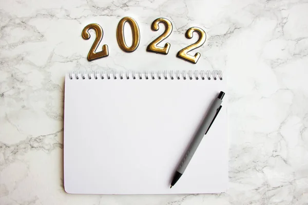 Boş bir sayfası olan bir defter, 2022 numaralı planlar için bir kalem.