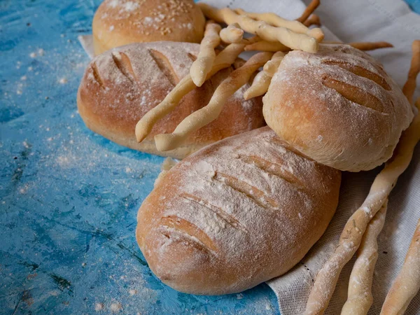 Итальянские хлебные палочки и хлеб. Вкусная ароматическая выпечка на голубом фоне. — стоковое фото