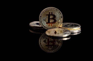 Yansıtıcı yüzeyi olan siyah bir arkaplanda Bitcoin yakın plan..