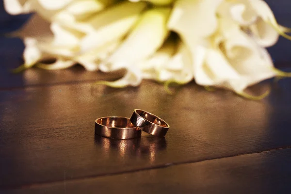 Anillos de boda y un ramo de lirios blancos — Foto de Stock