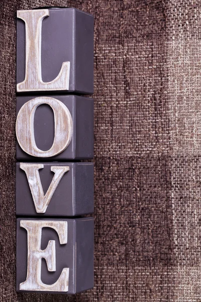 Slovo láska z krychlí na hnědé pozadí — Stock fotografie