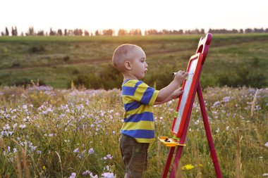 küçük çocuk boyalar bir tuval üzerine Peyzaj açık havada
