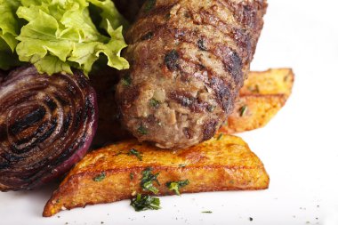 et, patates ve beyaz bir plaka üzerinde otlar ile çanak