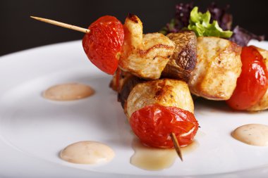 Tavuk kebap şişleri domates üzerinde