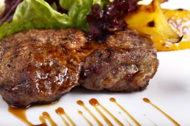 et, patates ve beyaz bir plaka üzerinde otlar ile çanak
