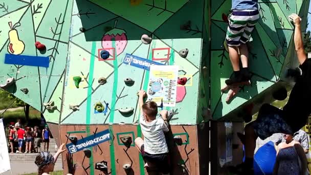Відкритий стіни для скелелазіння, діти та дорослі намагаються піднятися вгору — стокове відео