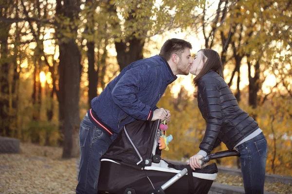 Gelukkige ouders op een wandeling met wandelwagen — Stockfoto