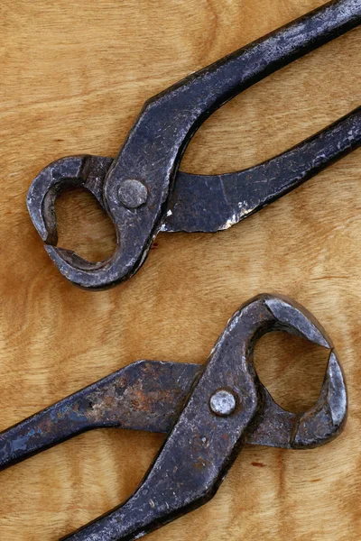 Old vintage tongs tool on a wooden background — Stock Photo, Image