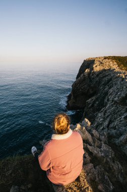 Pembe ceketli kadın Atlantik Denizi 'ne bakıyor.