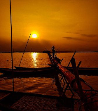 Bu yüksek kontrastlı manzara, parlak turuncu, kırmızı ve sarı katmanlı palmiye ağaçları ve tropikal orman siluetlerinin arkasındaki çarpıcı günbatımını yakalar..