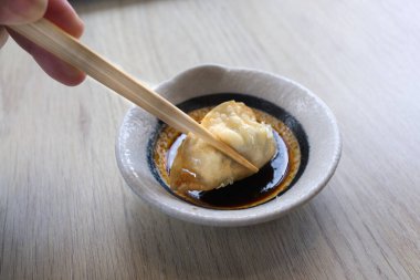 Elleri çubuklarla kızartılmış bir parça gyoza tutuyordu.