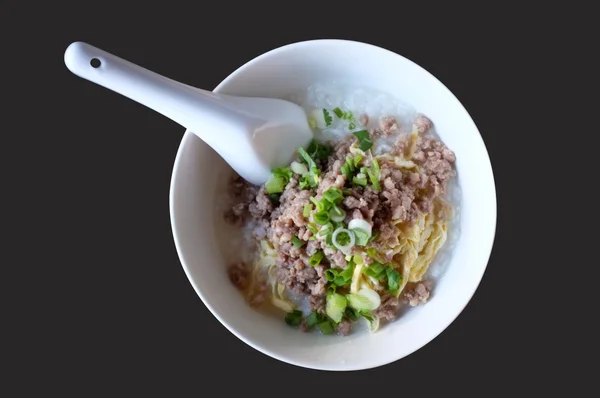Weich gekochter Reis mit Schweinehack, Congee in weißer Schüssel isoliert auf schwarzem Hintergrund — Stockfoto