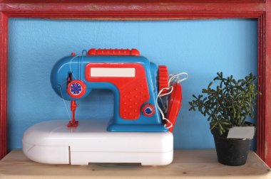 Bitki pot ile mavi arka plan üzerinde oyuncak ve vintage dikiş makinesi
