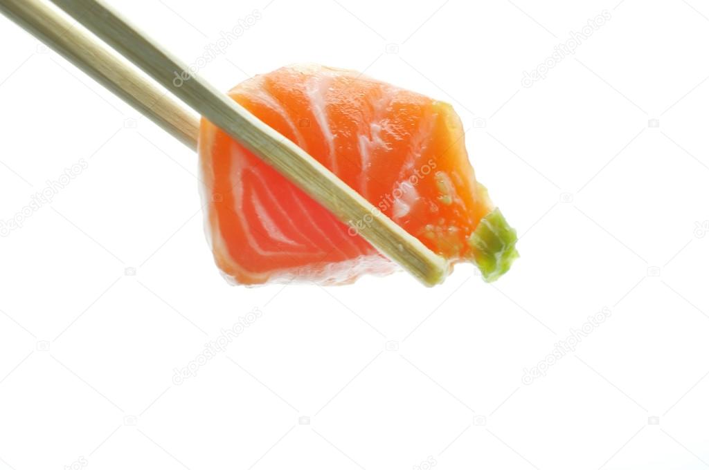 Chopsticks pinch fresh salmon sushi and wasabi