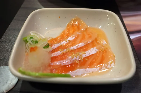 Slice of raw salmon in spicy salad sauce — Stock Photo, Image
