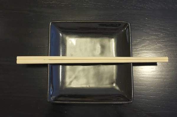 木製のテーブルに割り箸と黒い四角形皿 — ストック写真