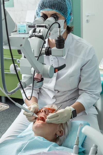 El médico dental examina al paciente con un microscopio . — Foto de Stock