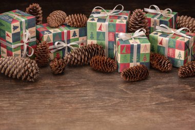 Noel ve Yeni Yıl selamları. Çam kozalakları ve siyah ahşap arka planda hediyeler olan tatil kutuları..