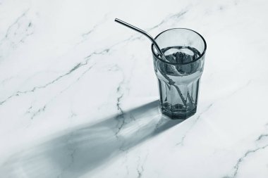 Bardakta temiz su ve pipet. Sağlıklı yaşam tarzı kavramı. Mermer yüzeyde yansıma.
