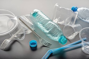 Kullanılmış tek kullanımlık sofra takımı, gri arkaplan. Plastik atıkların ekoloji ve geri dönüşümü kavramı.