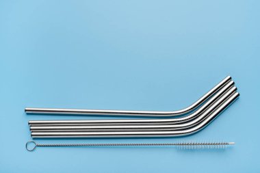 Yeniden kullanılabilir metal içecekler pipet ve temizleme aracı mavi arka planda fotokopi alanı ile. Yakın çekim, stüdyo çekimi..