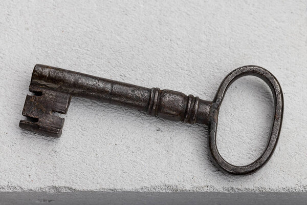 Door key, old metal, on a gray porous surface.