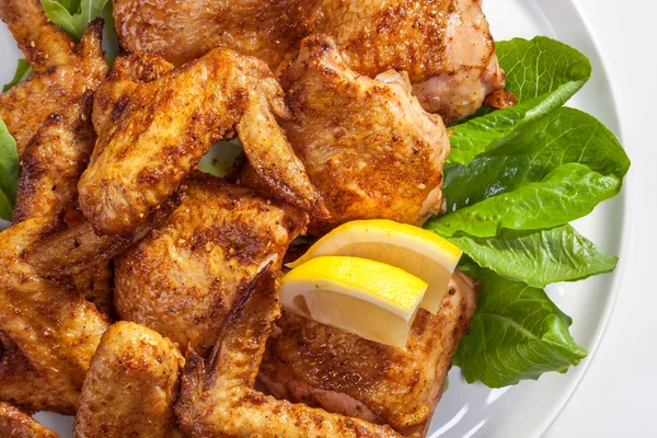 Baked chicken wings with a green salad and lemon — Stock Photo, Image