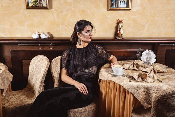 Lady in evening dress at a table in a cafe — Stock Photo, Image