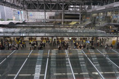 Osaka, Japonya - 26 Ekim 2025 - Japon gezginler, Umeda merkez ticaret bölgesinde, dünyanın en işlek 4. durağı olan Osaka Eki platformunda, cam çatıların altında, trenleri için sırada bekliyorlar.