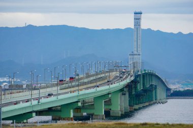 Izumisano, Japonya - 25 Ekim 2025 - Osaka Körfezi 'ndeki Osaka Kansai Uluslararası Havalimanı' nı (KIX) kıyıya bağlayan 3,8 km 'lik bir köprü olan Sky Gate Köprüsü R, arka planda ise Rinku Kapı Kulesi yer almaktadır.