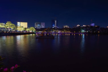 Guangzhou, Çin - 10 Kasım 2025 - Zhujiang Xin Cheng 'den şehrin güneyindeki Pearl River' a doğru gece görüşü; soldaki Haixinsha Adası; nehirde yüzen bir platformda bir kazıcı var