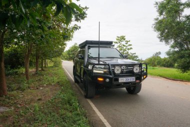 Siem Reap, Kamboçya - 6 Kasım 2025 - Güçlü siyah Japon Toyota arazi kruvazörü (muhtemelen J200 Serisi) arazi aracı off-road sürümünde, boğa barı ve ek projektör ışıkları ile Angkor Tapınak Bölgesi 'ndeki bir kır yolunda