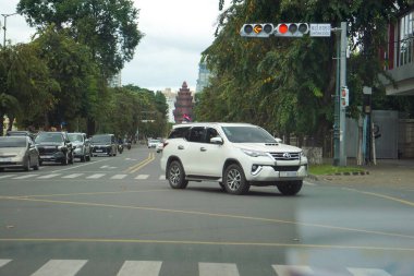 Phnom Penh, Kamboçya - 4 Kasım 2025 - Preah Norodom Bulvarı 'nda Toyota Fortuner (kapalı Hilux), Maybach GLS SUV, Lexus LM MPV ve Toyota Prius dahil olmak üzere uzak otomobil trafiği