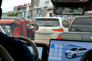 Phnom Penh, Kamboçya - 8 Kasım 2025 - Çin yapımı bir BYD Xia eMAX9 MPV 'den görülen trafik, bir tuk-tuk ve iki Japon kamyonu: Lexus LX 570 lüks bir SUV, ve bir Nissan kamyonet, muhtemelen Navara