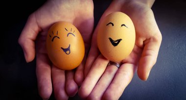 İki Paskalya yumurtası elinde neşeli bir yüz şeklinde süslenmiş.