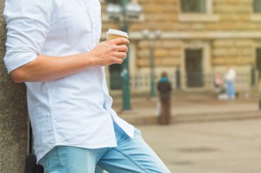 Bir adam ara verip sokakta kahve fincanı içiyor..