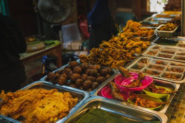 Geleneksel bir Wedangan 'da zengin bir Endonezya meze (lauk) gösterisi. Tepsilerde kızarmış balık, haşlanmış bıldırcın yumurtası (sate puyuh), kızarmış tavuk ve omlet, işlek mutfak arka planına sahip kırsal bir sokak yemeklerinde servis edilir..