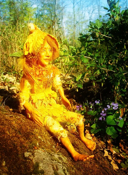 Patung peri bersinar emas duduk di atas batu di hutan Stok Foto