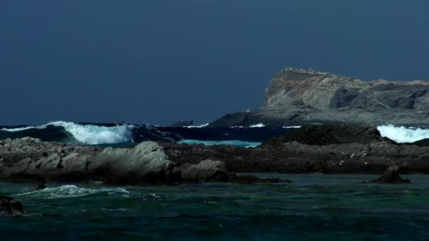 Волны ломаются на каменистом берегу — стоковое видео