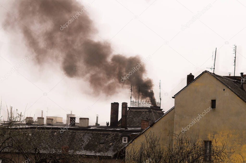 Black coal smoke coming from a domestic chimney in a city.