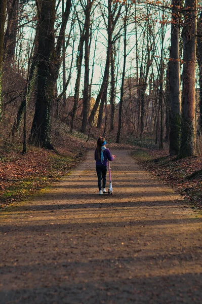 Langharig Meisje Loopt Met Een Scooter Een Pad Tussen Bomen — Stockfoto