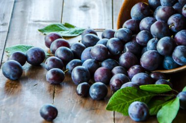 Olgun erik kil bir bardaktan ahşap bir masaya saçılmış.