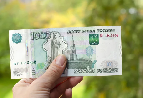 A Russian banknote with a face value of 1000 rubles in the hand of a woman. The concept of finance, investment, savings and cash.