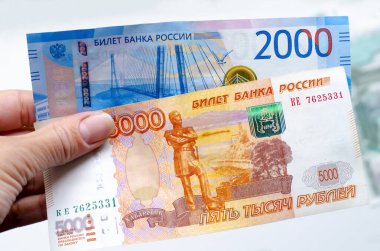 2000 ruble değerinde Rus banknotları ve bir kadının elinde 5000 ruble. Finans, yatırım, tasarruf ve nakit kavramı.