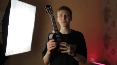 Günlük kıyafetli bir adam ukulele öğretir ve sosyal medya için bir video çeker.