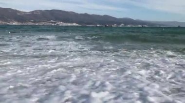 Arka planda dağ olan fırtınalı dalgaların geniş bir görüntüsü.