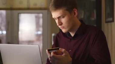 Genç adam online alışverişler için kredi kartıyla bilgisayar kullanıyor. yavaş çekim