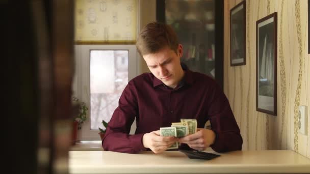 Felboncolt fiatal üzletember ellenőrzi a pénztárcáját és számolja a pénzt. A személy belenéz a pénztárcába pénz nélkül.. — Stock videók
