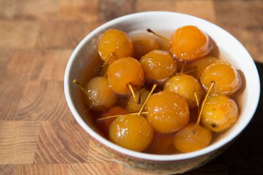 Ahşap bir tezgahın üzerinde porselen bir bardakta sarı renkte elmalardan yapılmış reçel..